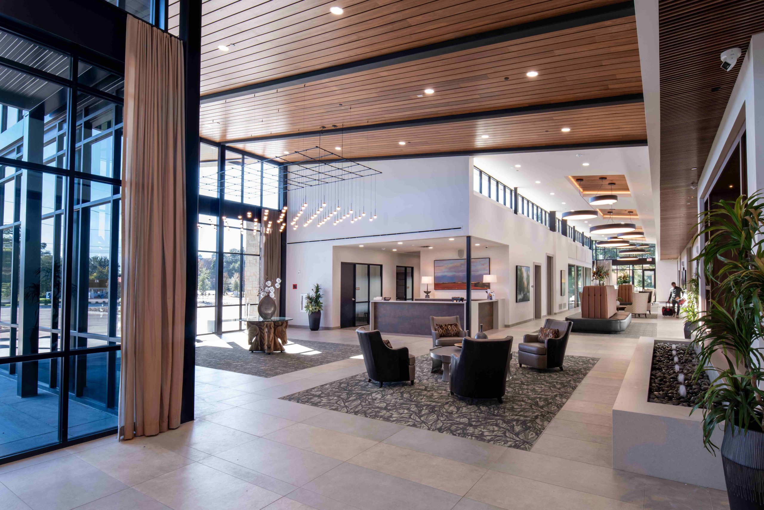 Modern lobby with travertine walls and wood paneling, an example of identity-driven interiors shaped by material and light.